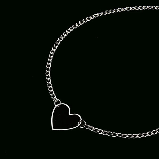 Close-up of delicate hollow heart pendant choker on dark background showing chain detail.